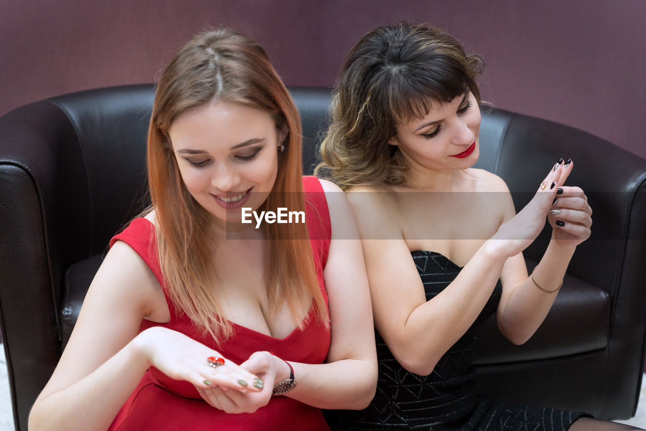 Smiling woman wearing rings while sitting on sofa