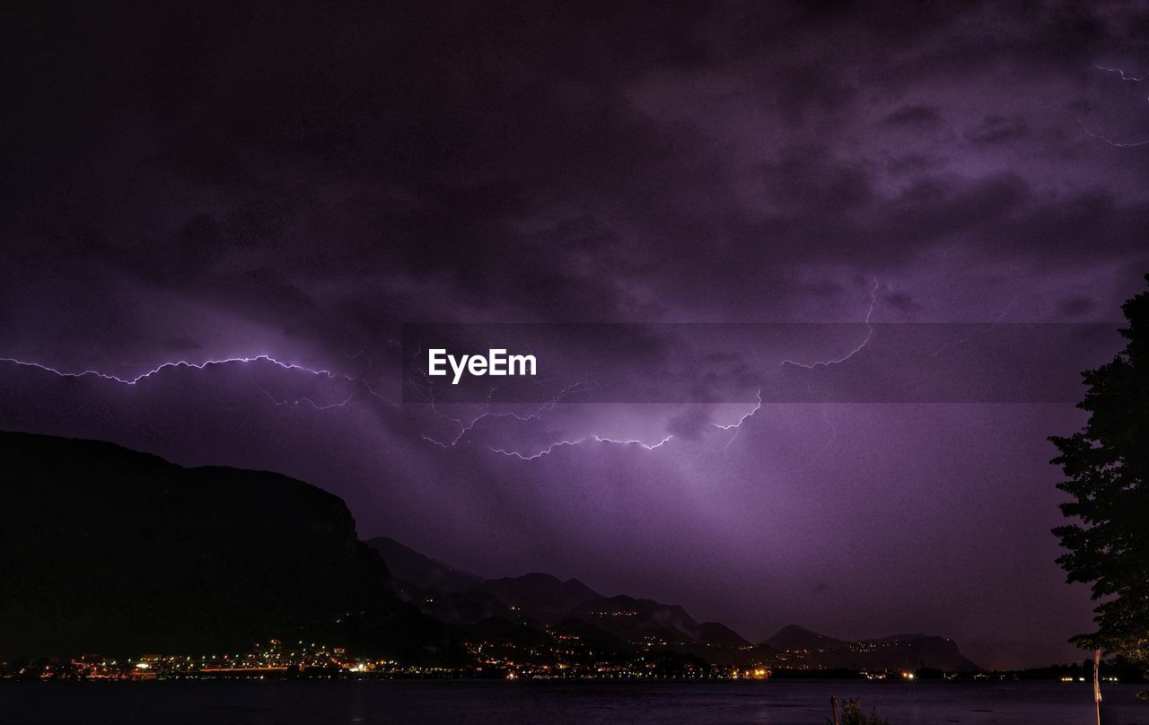 LIGHTNING OVER ILLUMINATED CITYSCAPE AGAINST SKY