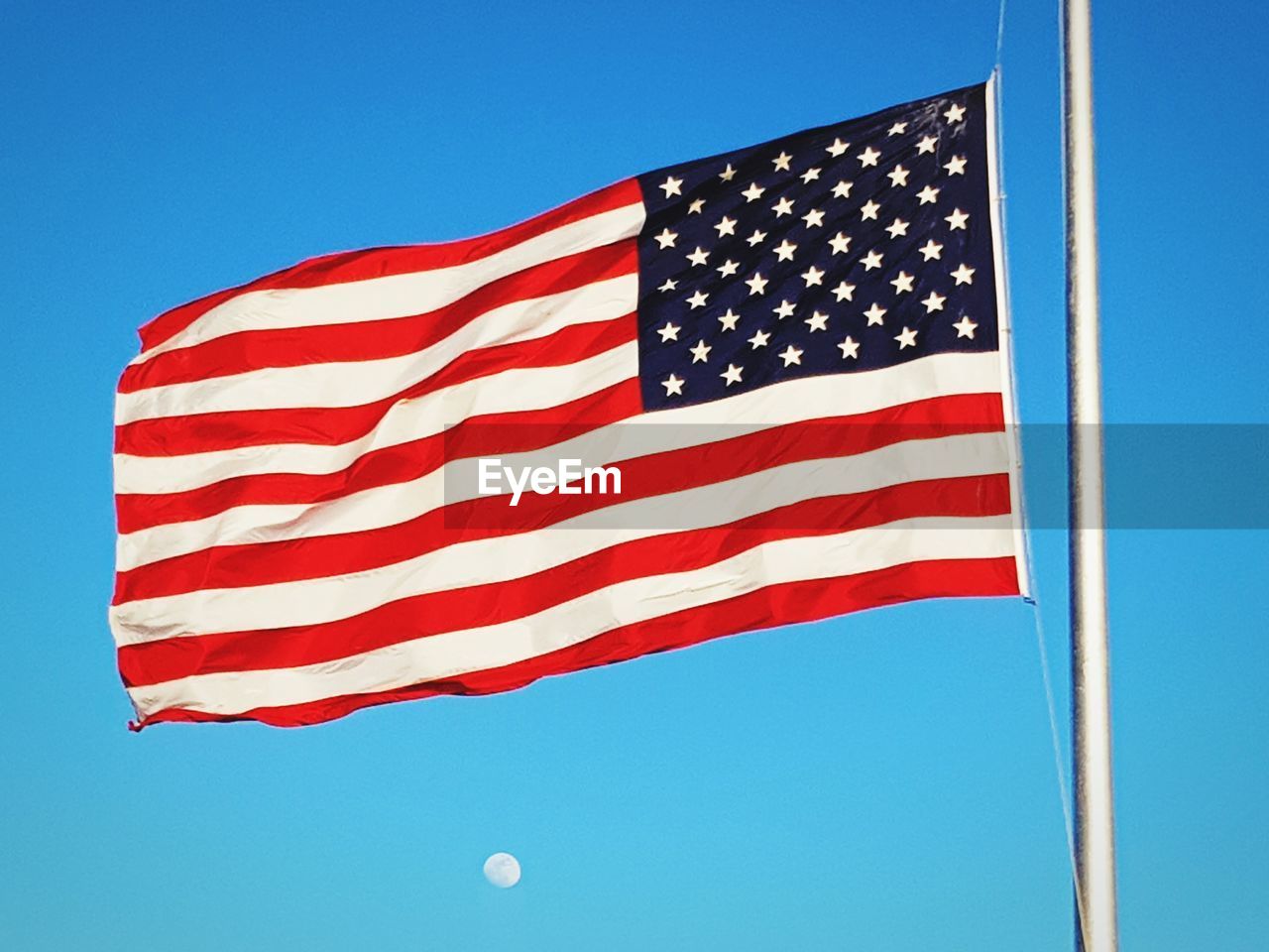 American flag waving against clear blue sky