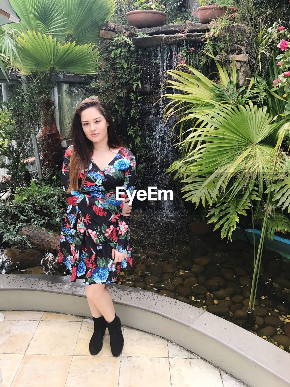 Portrait of beautiful woman standing against fountain at park