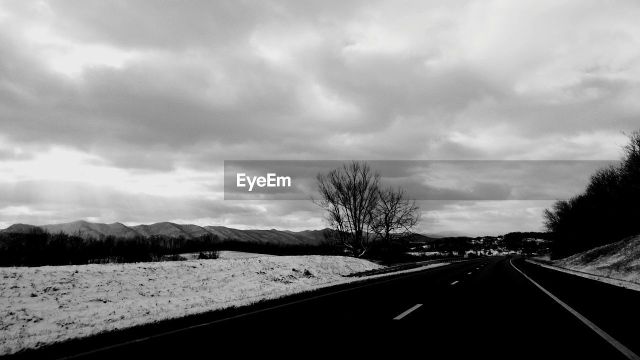 ROAD AMIDST SNOW COVERED LANDSCAPE AGAINST SKY