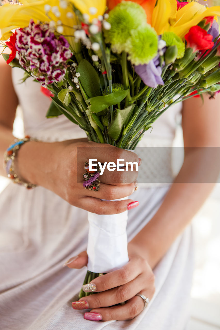 Midsection of bride holding colorful bouquet
