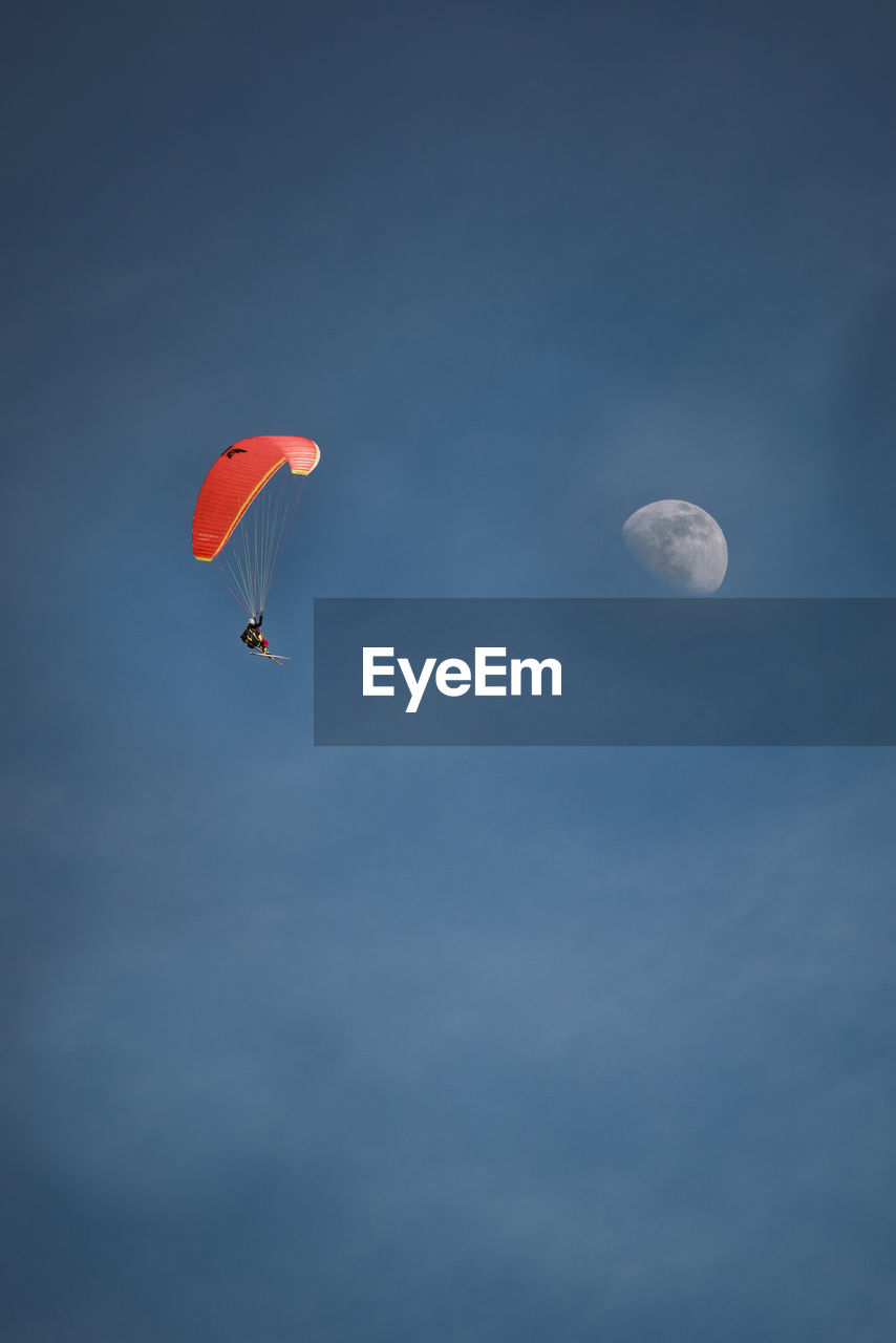 LOW ANGLE VIEW OF PEOPLE PARAGLIDING AGAINST MOON