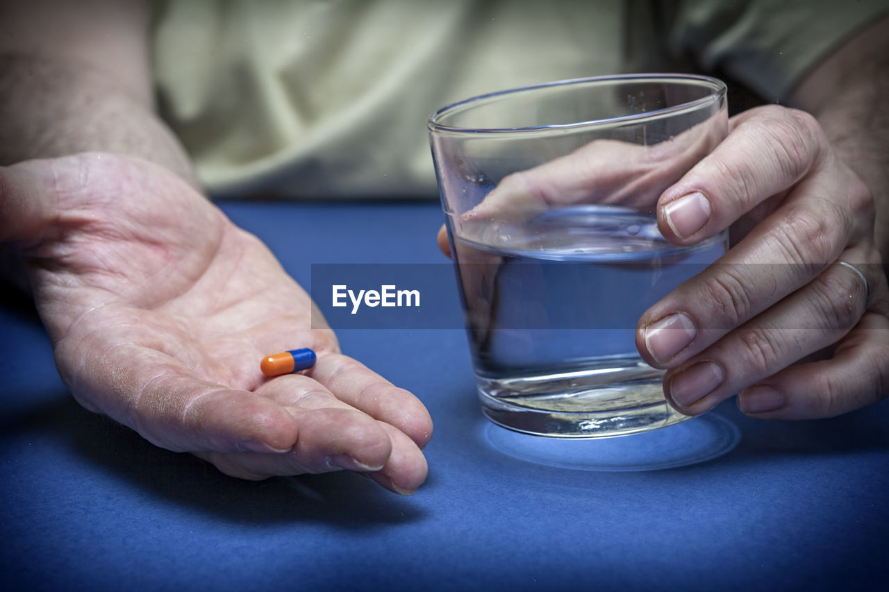 CLOSE-UP OF HANDS HOLDING GLASS OF JUICE