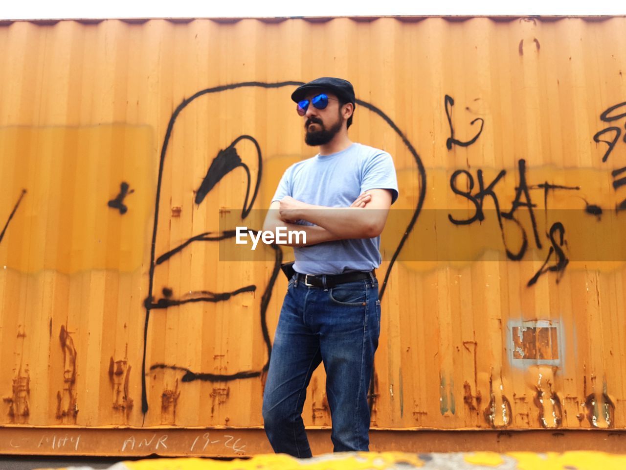 Man wearing sunglasses while standing against graffiti wall