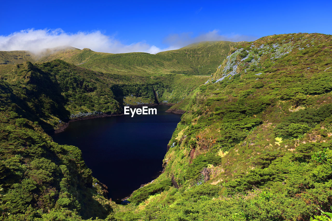 SCENIC VIEW OF RIVER AMIDST GREEN MOUNTAINS