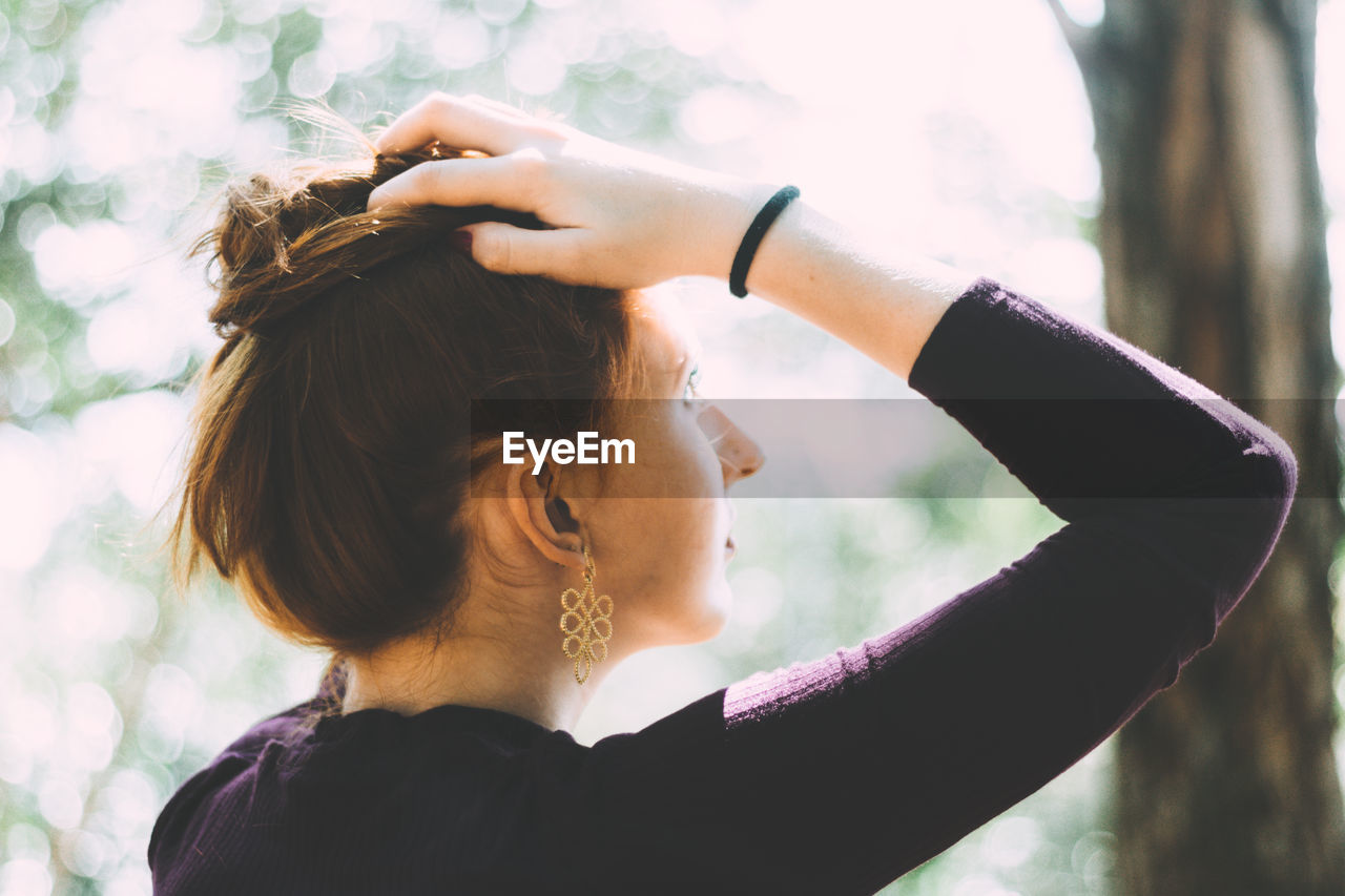 Close-up of young woman against trees