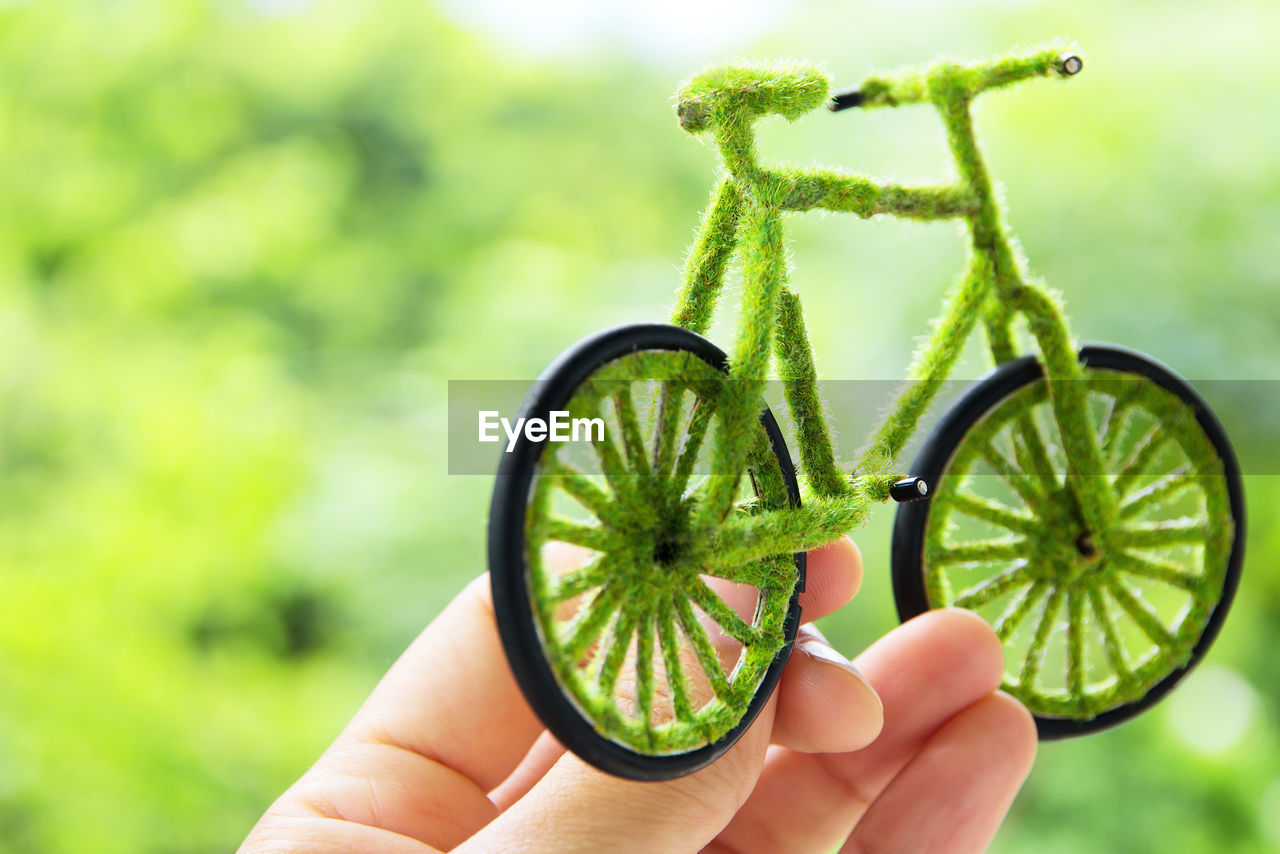 Cropped fingers of person holding toy bicycle