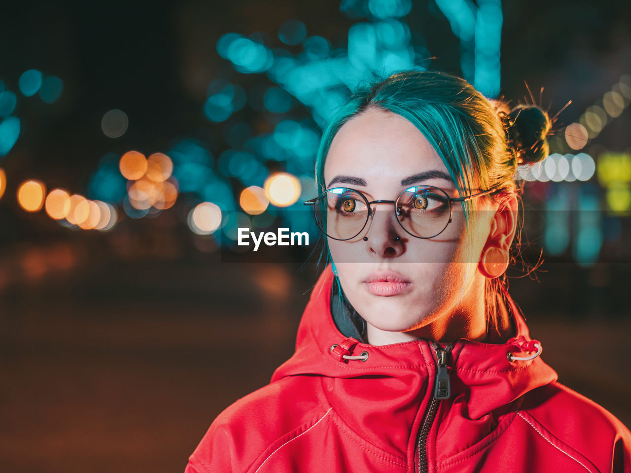 Close-up of young woman wearing eyeglasses while standing outdoors at night