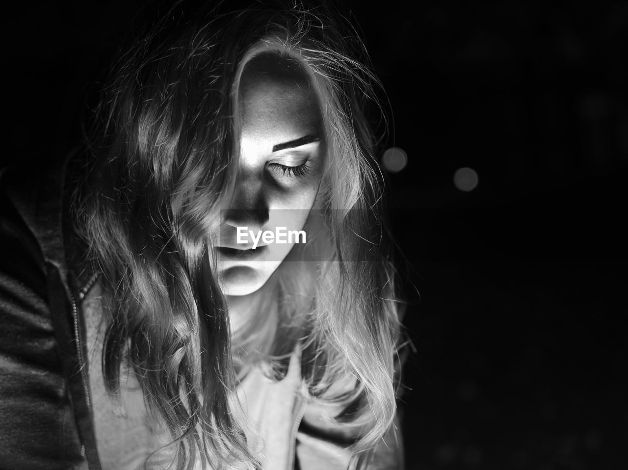 Woman with closed eyes against black background