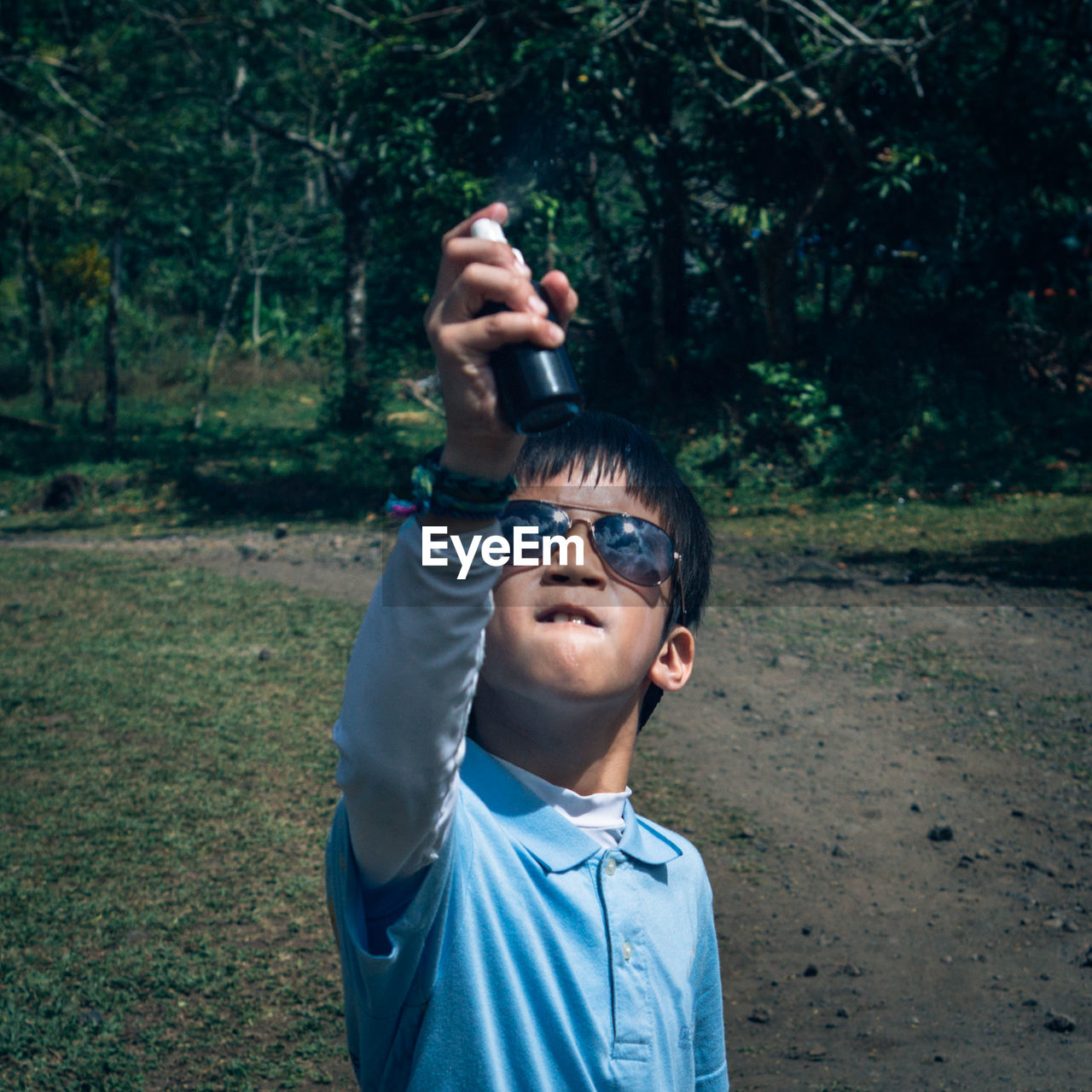 Boy holding perfume sprayer while standing on field