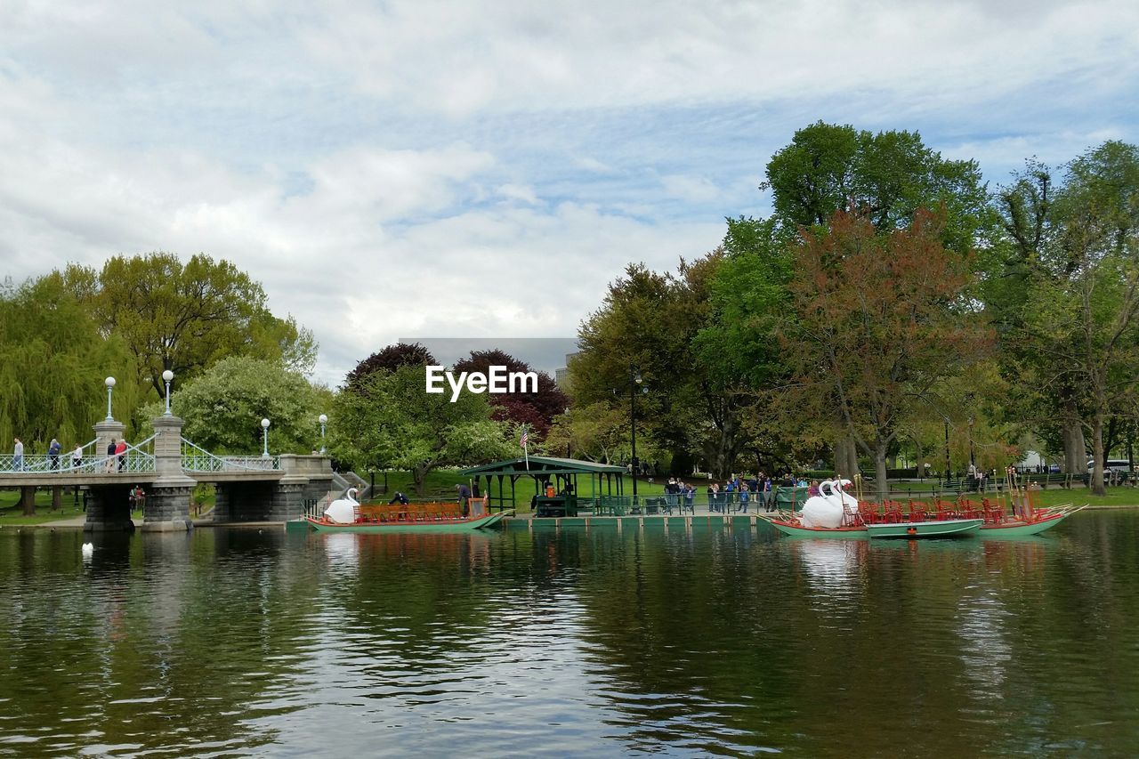 BOATS SAILING ON LAKE AGAINST TREES