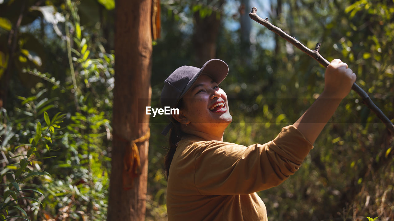 Smiling woman holding branch outdoors