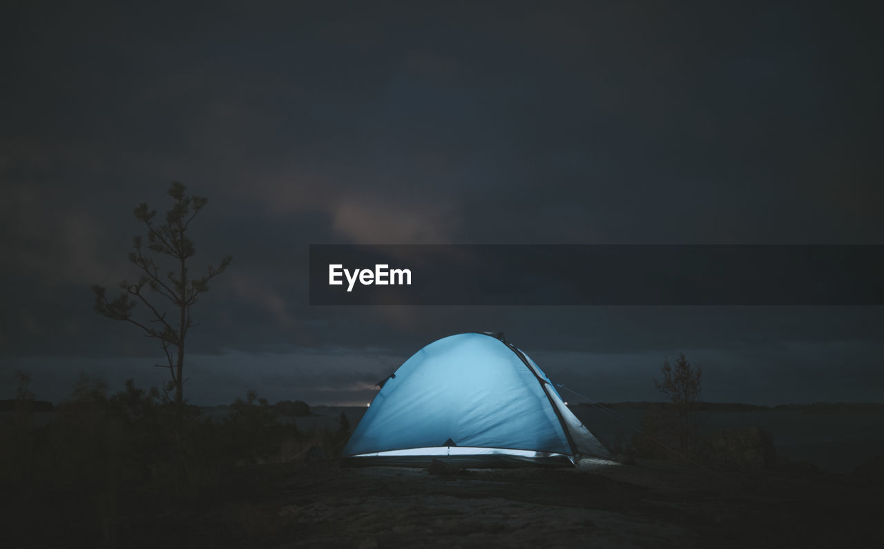 Lonely luminous tent in a remote location on a cloudy night. themes of tourism and active lifestyle.