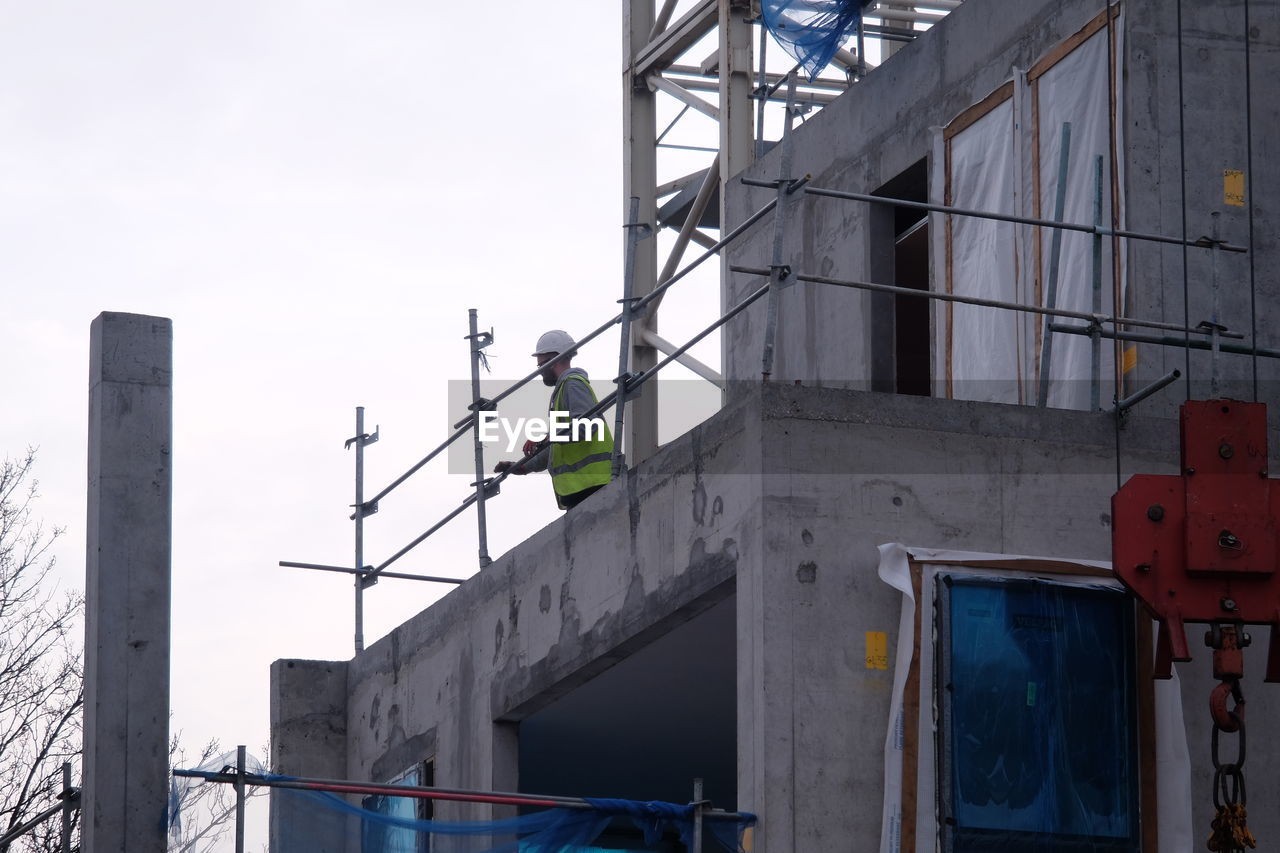Low angle view of construction worker on building against clear sky