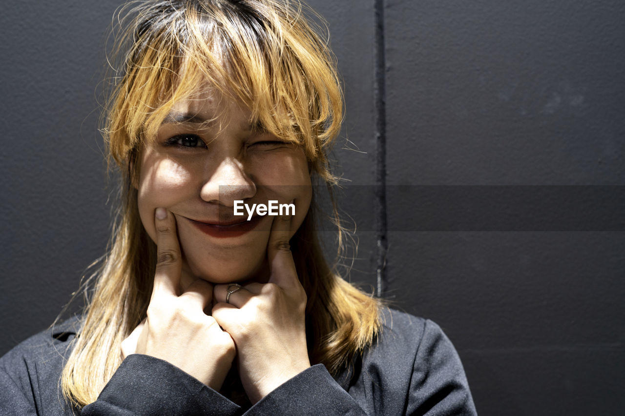 Close-up portrait of smiling businesswoman against wall