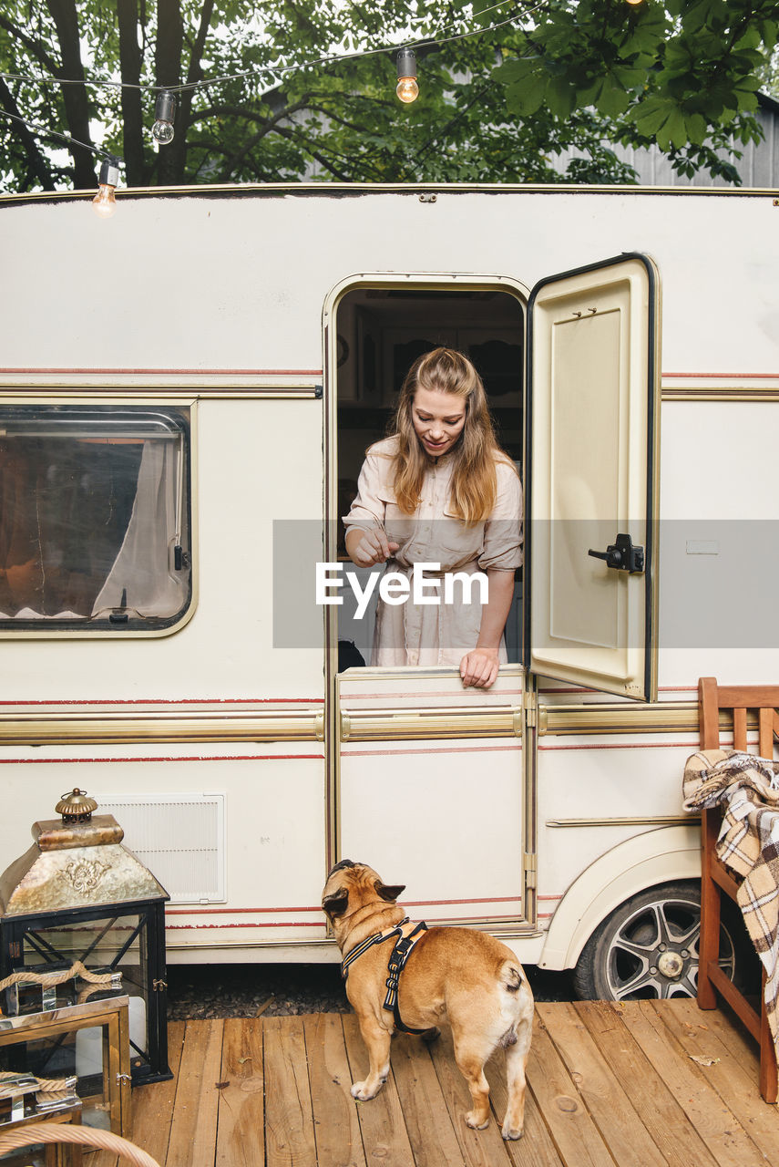 Camping and travelling . happy person relaxing outdoors near trailer. woman with dog is ready for