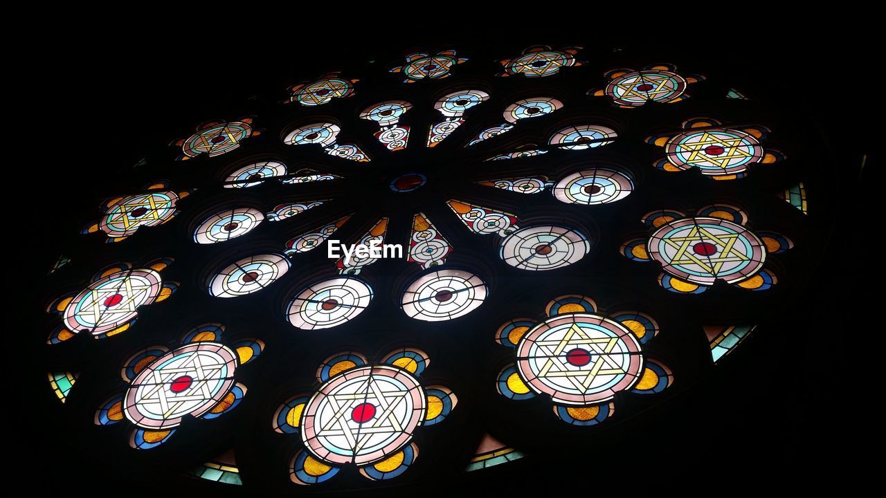 LOW ANGLE VIEW OF MULTI COLORED LIGHT BULBS IN BLACK BACKGROUND