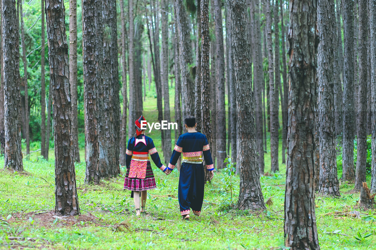 Couple hmongs holding hands and walking in the pine wood, man and woman in hmong clothes