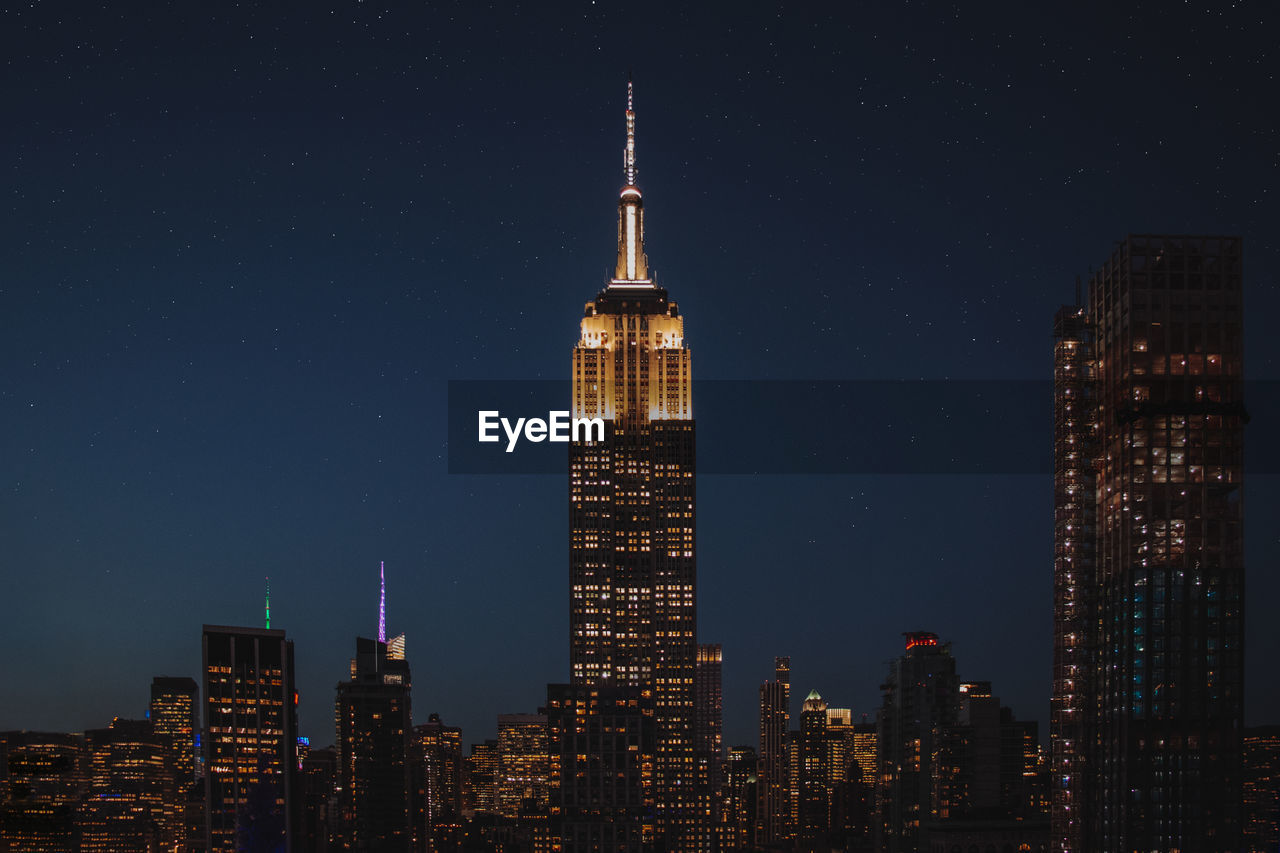 Illuminated empire state building in city at night