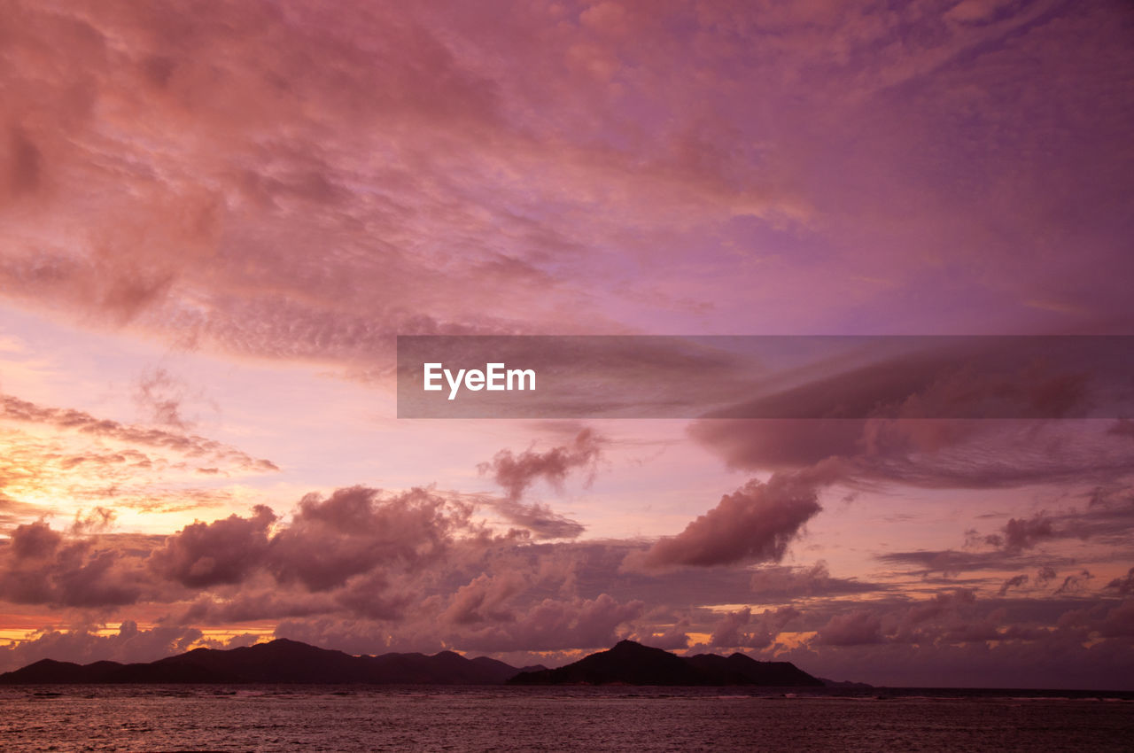 Beautiful tropical sunset over the sea horizon with black silhouette of an island. seychelles