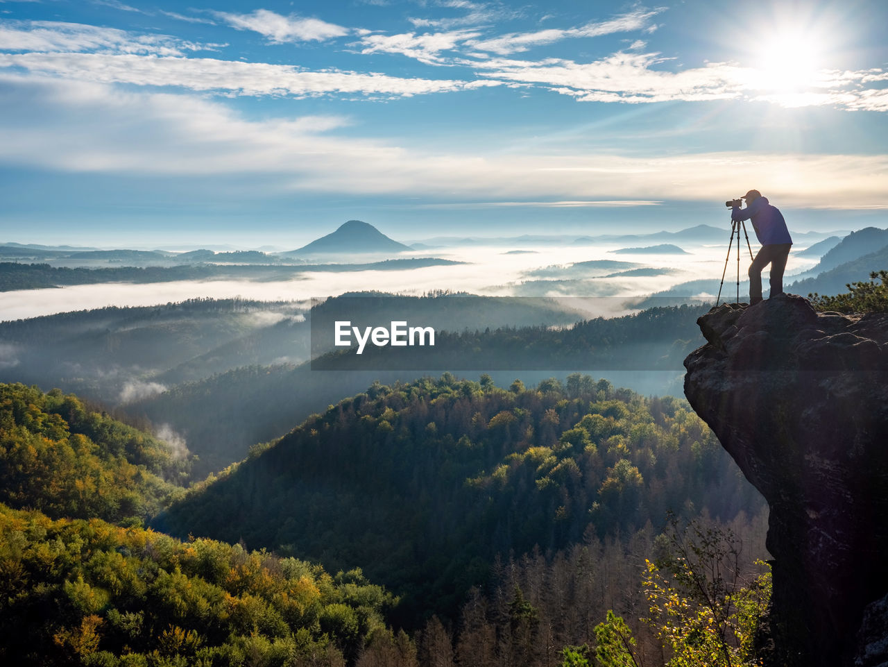 Man holding camera in his hands and making photos of the mountains during autumn morning