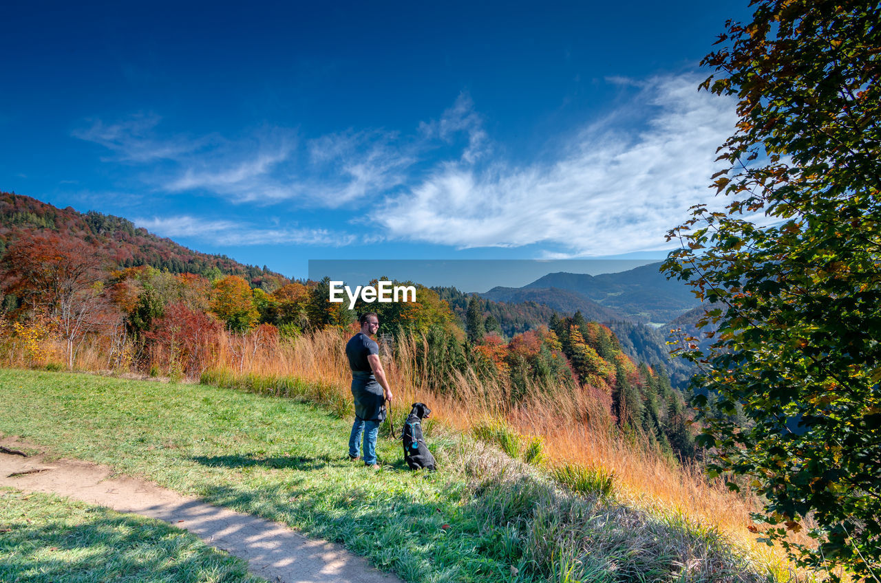 Man with dog standing on land against sky