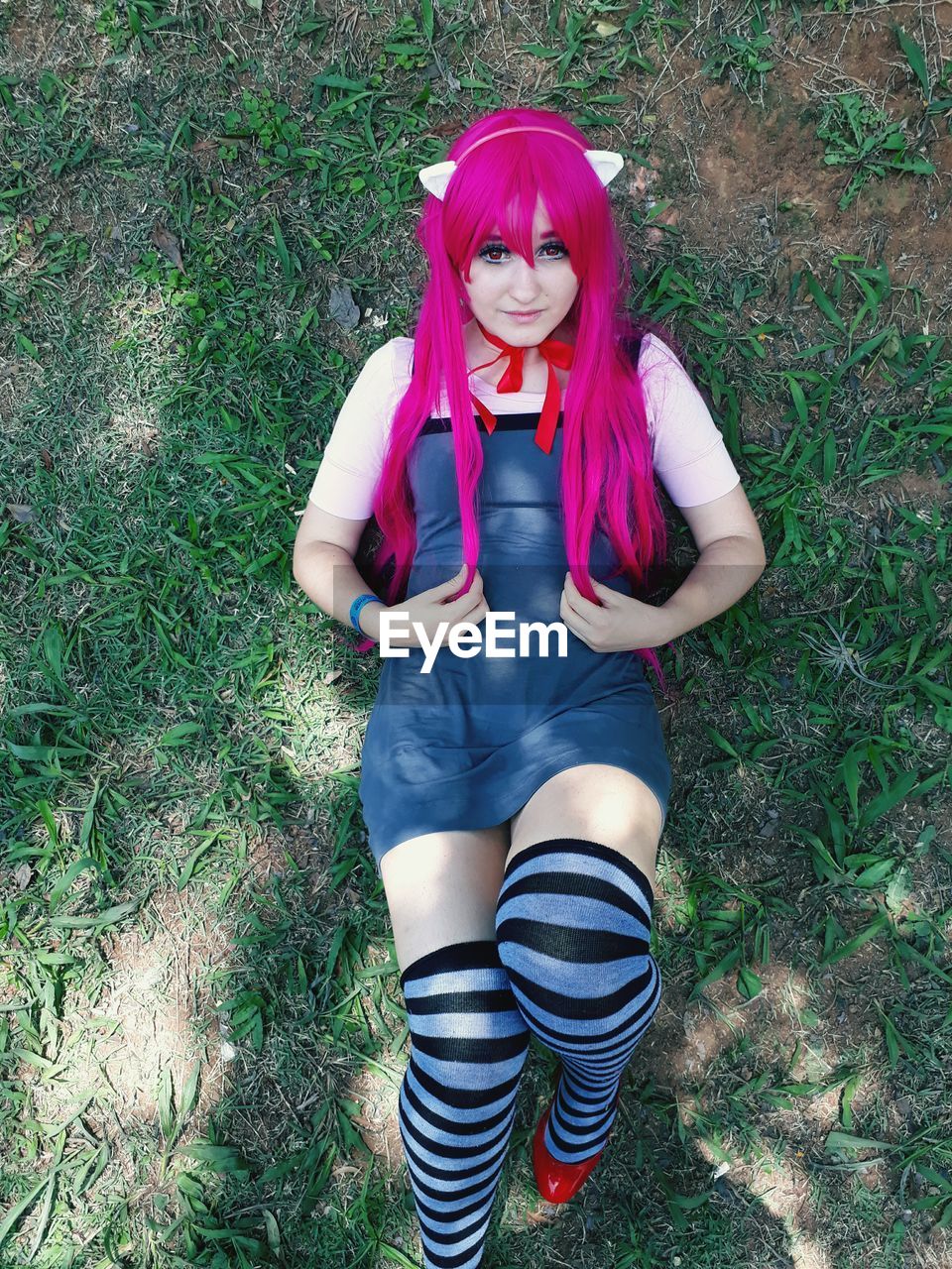 Portrait of young woman wearing cosplay costume while lying on grassy field