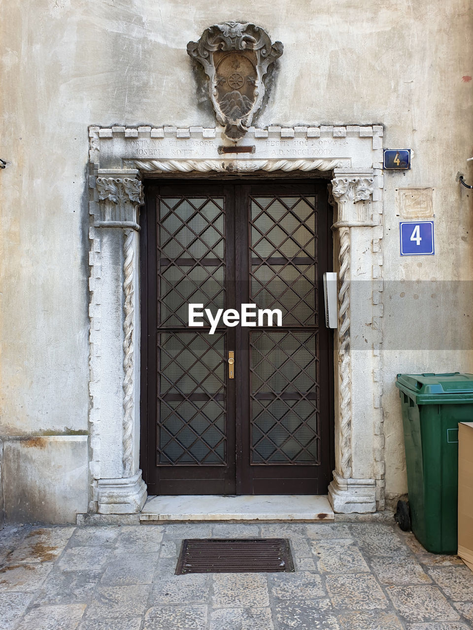 Glass door with brown frame against ornate stone framework located at zadar, croatia