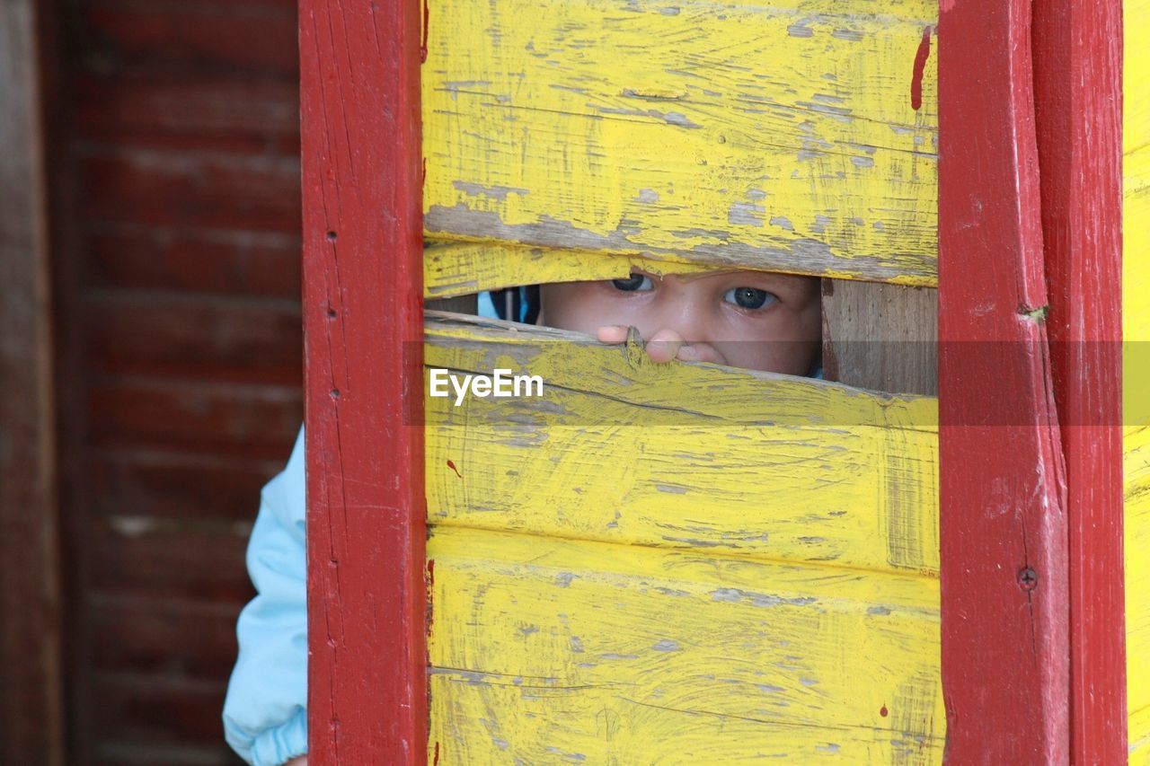 Boy peeping through wooden window
