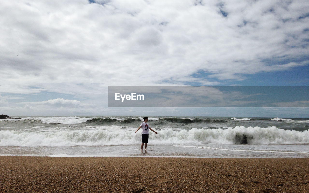 Man standing at beach against sky