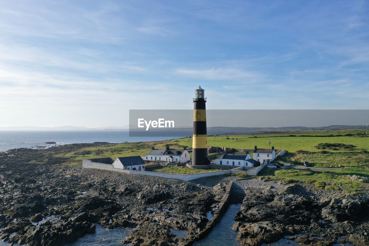 Lighthouse amidst buildings against sky