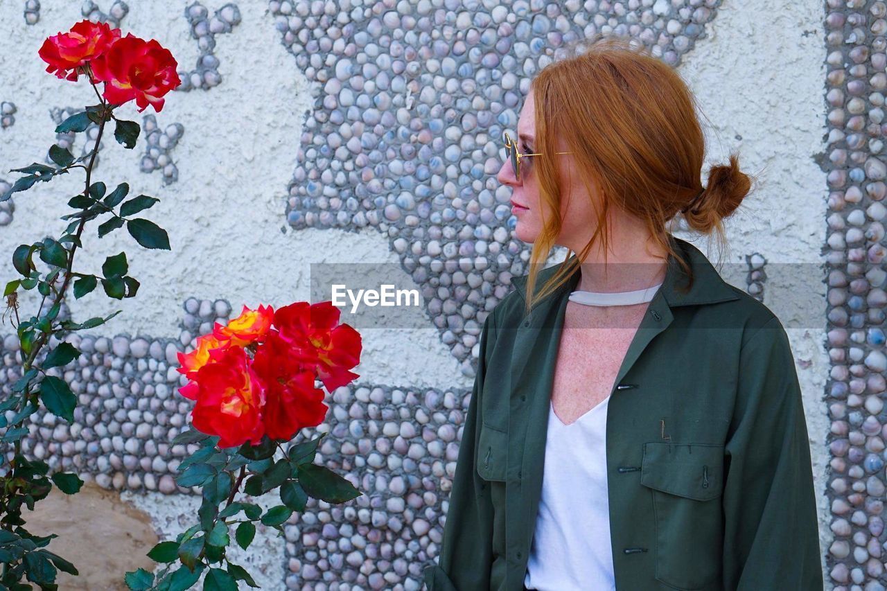 Young woman standing by flowers