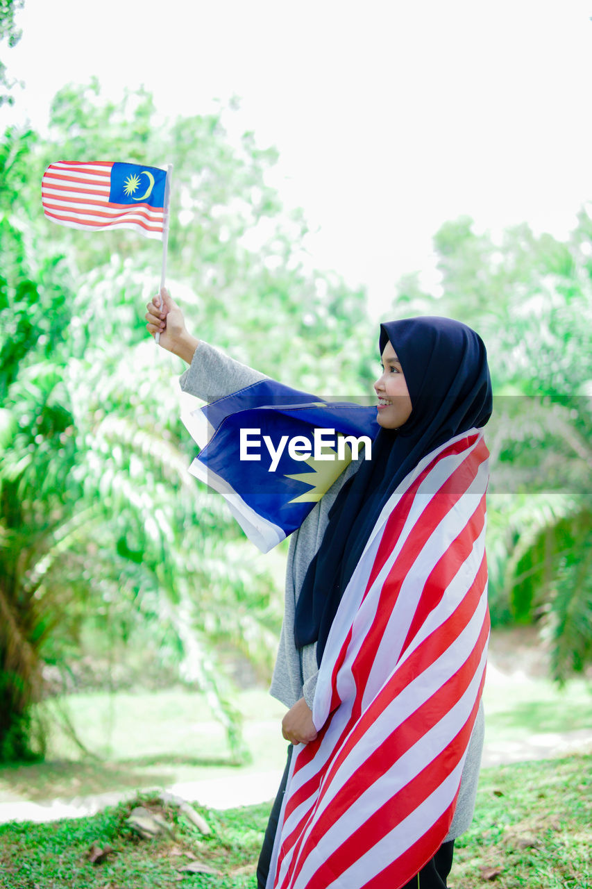 Muslim woman happy holding a malaysian flag. malaysia independence day.