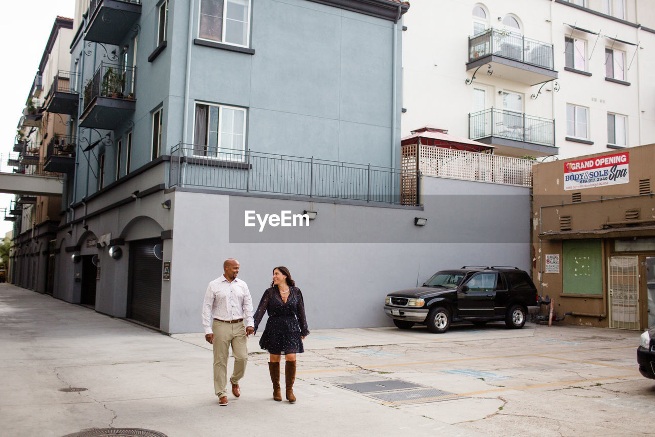 Late forties couple holding hands walking in alley in san diego