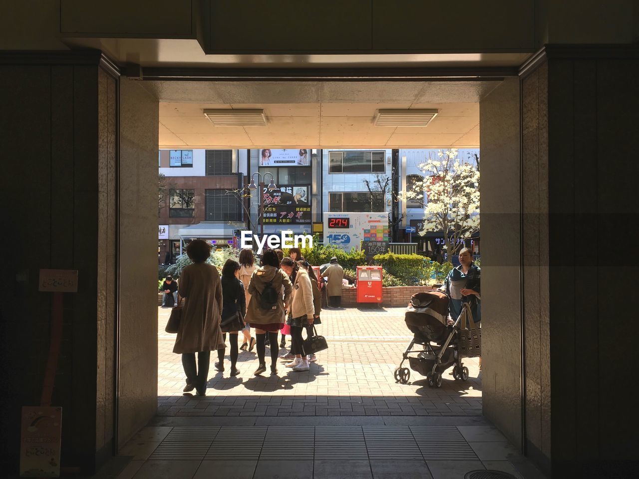 REAR VIEW OF PEOPLE WALKING ON STREET AMIDST BUILDINGS