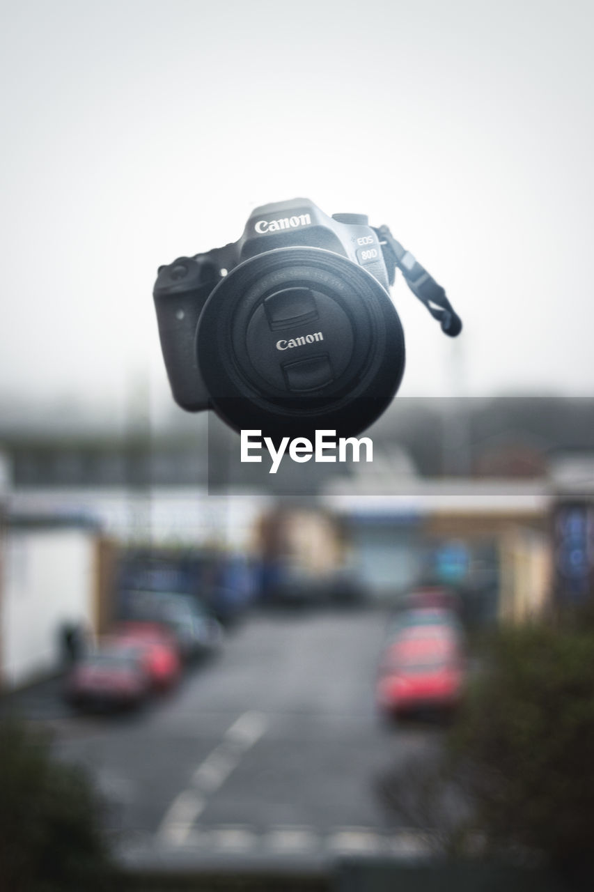 CLOSE-UP OF CAMERA ON CITY STREET