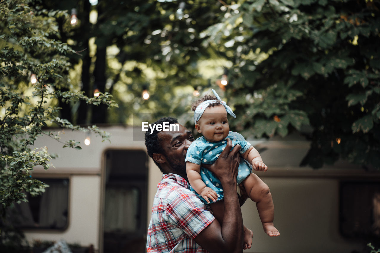 Father carrying daughter on shoulder outdoors