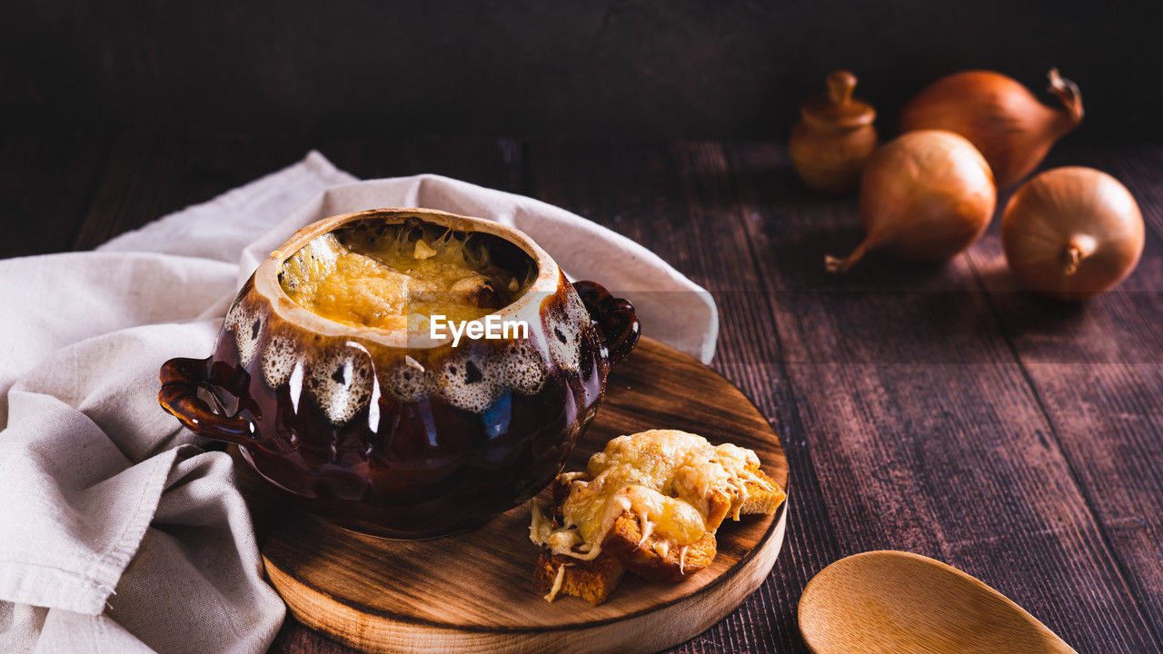 French onion soup with melted cheese and croutons in a pot on the table web banner