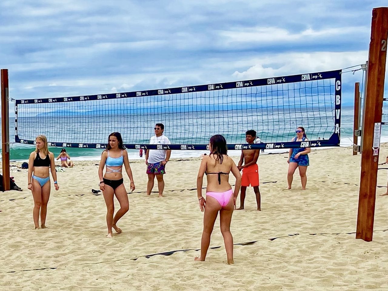 beach volleyball, volleyball, net sports, group of people, beach, land, sky, ball game, sand, sports, team sport, nature, sea, adult, women, men, clothing, leisure activity, lifestyles, cloud, holiday, water, young adult, summer, vacation, trip, player, day, swimwear, motion, large group of people, full length, outdoors, crowd, fun