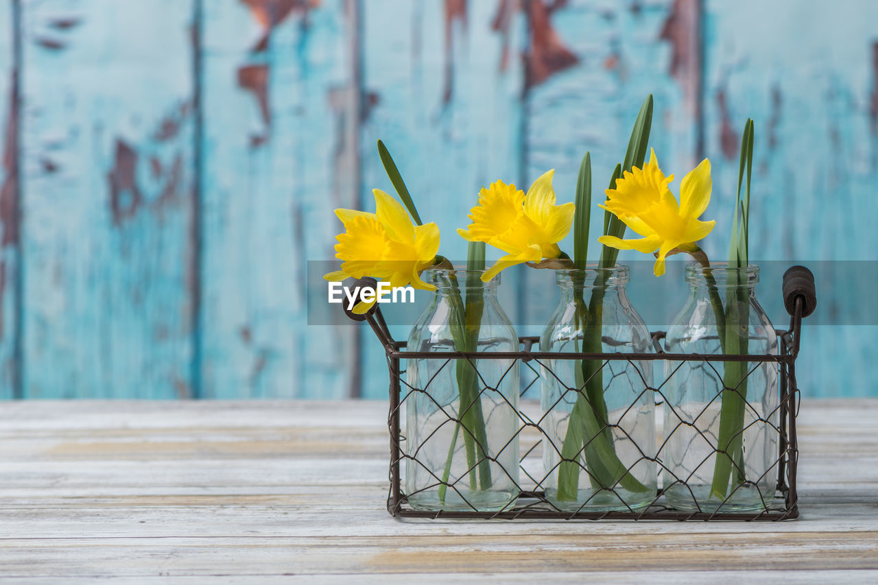 CLOSE-UP OF YELLOW FLOWERS ON WOODEN TABLE