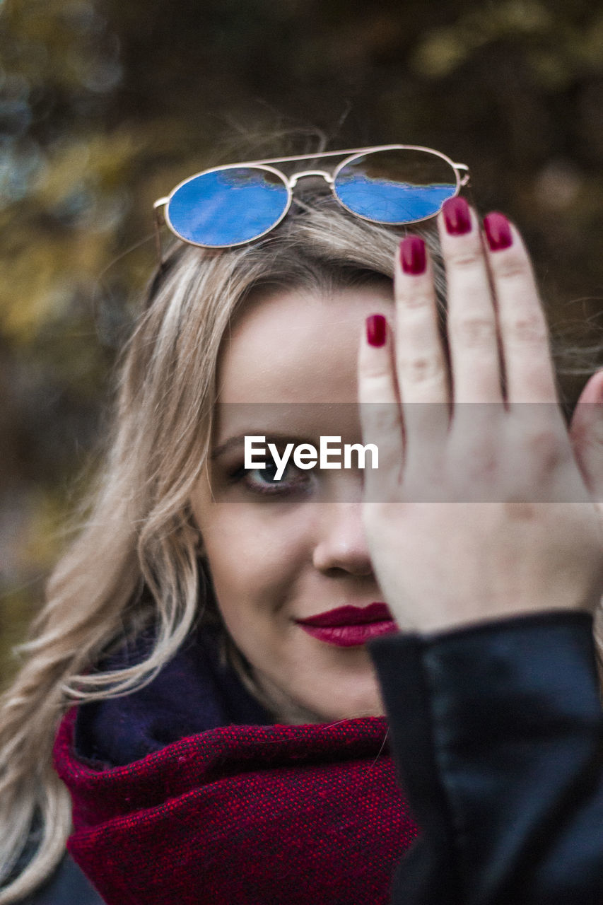 Portrait of woman covering eye with hand