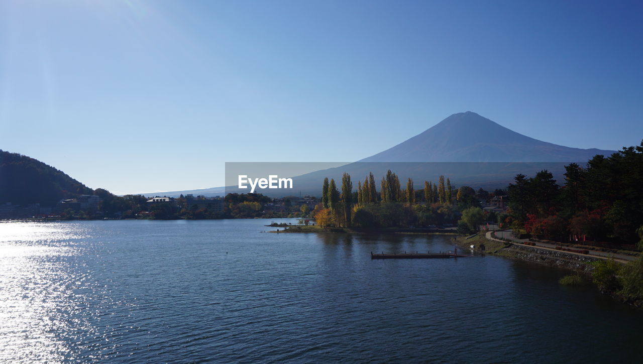 Scenic view of lake and mountains against clear blue sky