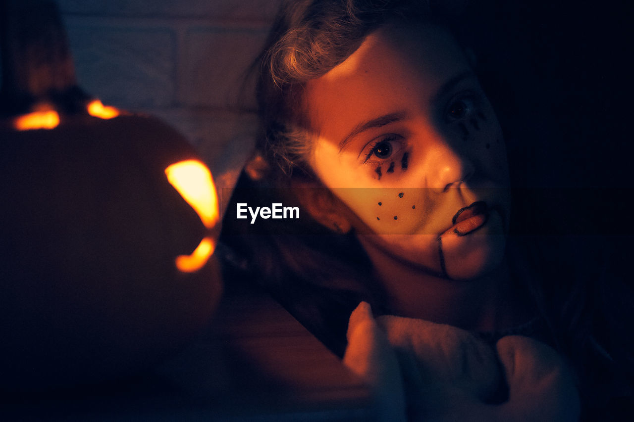 Cute girl wearing costume standing by pumpkin during halloween