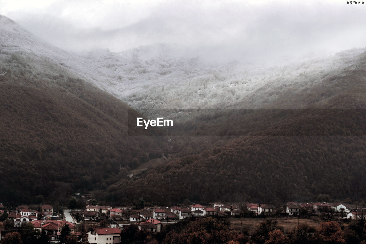 Scenic view of town by mountains against sky