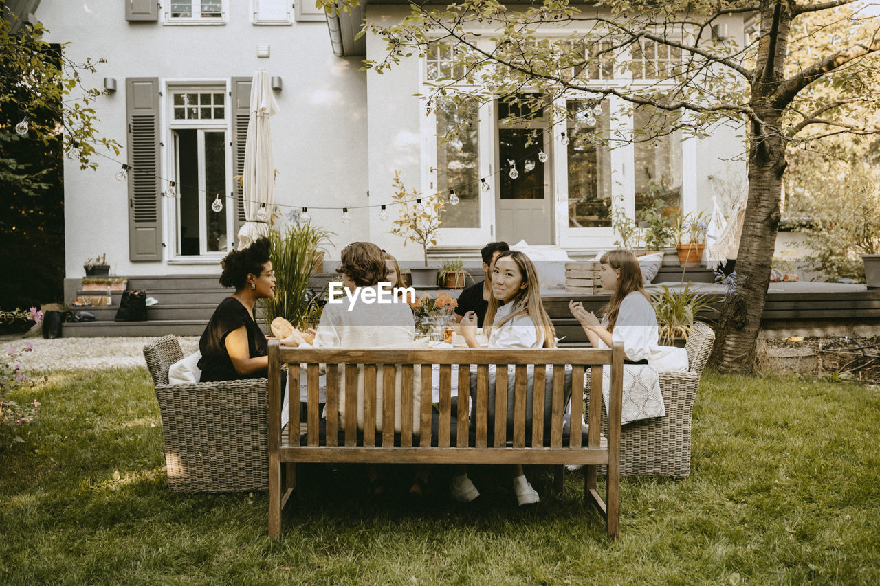 Portrait of smiling woman sitting with friends by table during garden party