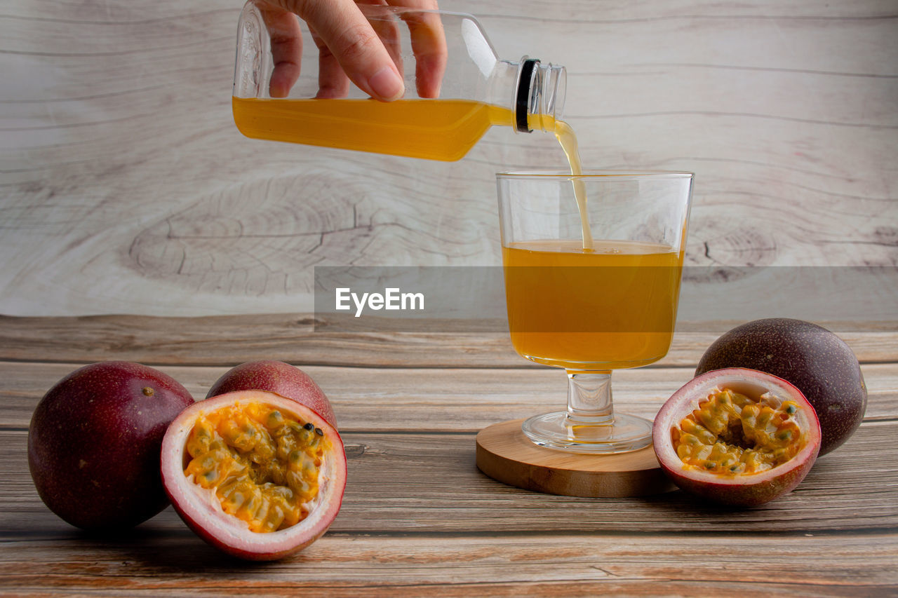 Fresh passion fruit juice in glass with passion fruits on wood background.