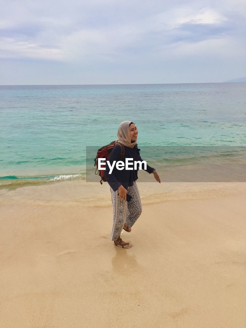 Full length of woman standing on beach against sky