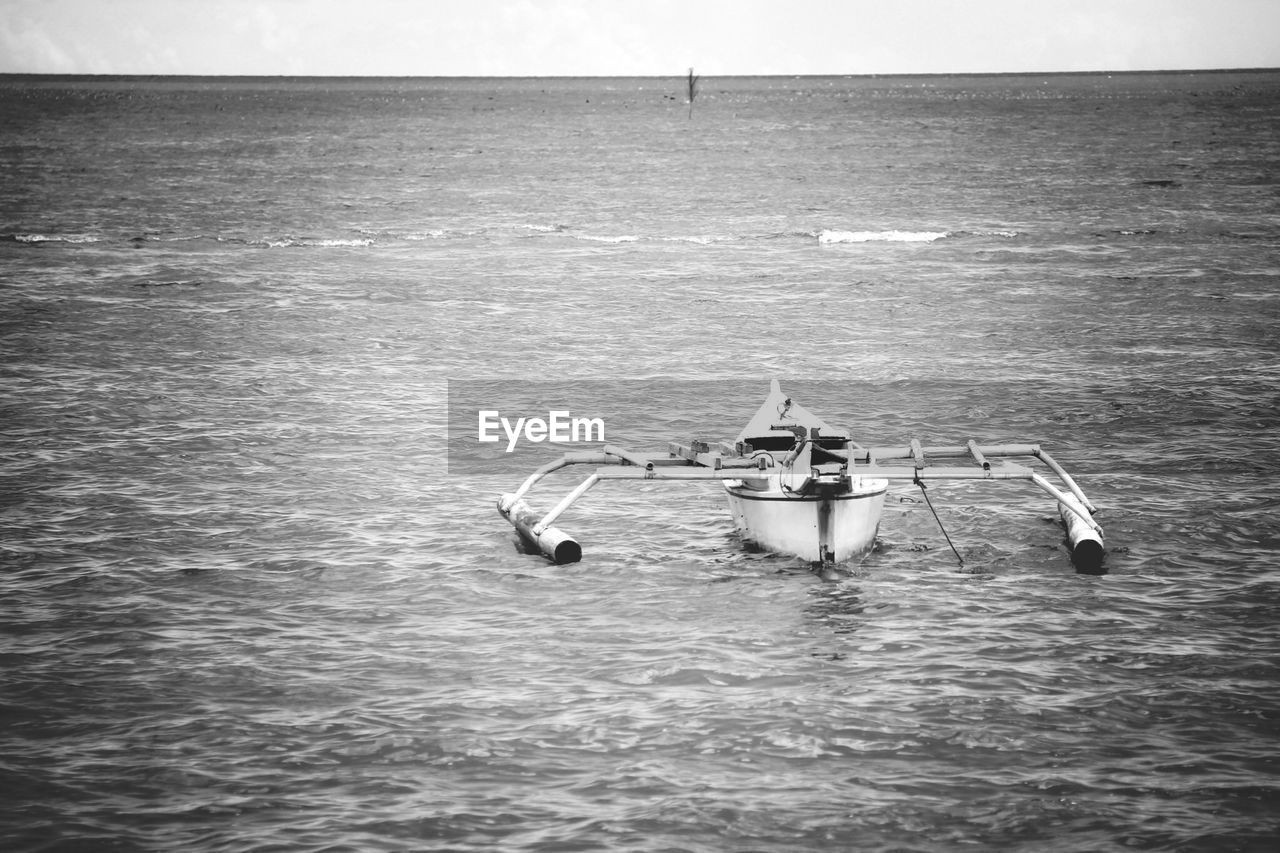 Outrigger moored on sea against clear sky