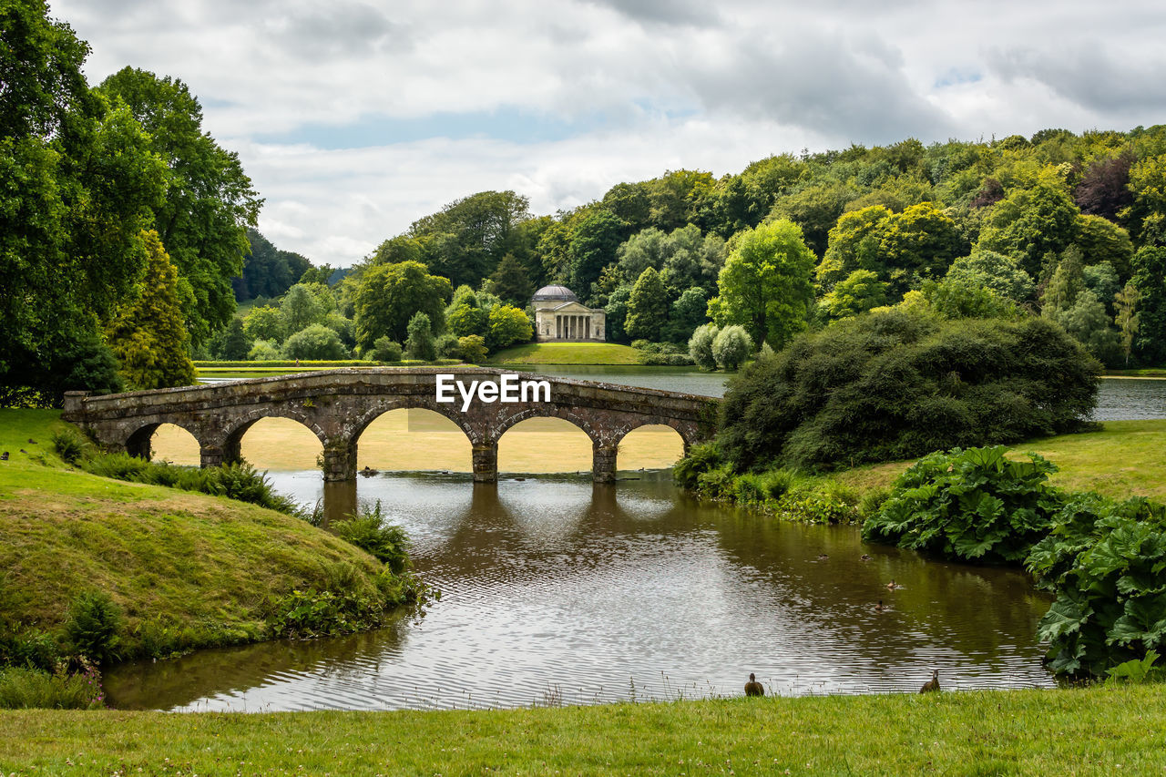 Arch bridge over river against sky